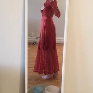 Långklänning - Jättefin långklänning med spetsarmar och plisserad kjol. Rönnbärsfärgad, silkesplisserad. Spetsrygg och knäppning där bak. Perfekt till bröllop, bal eller fibare fest. Använd en gång! 