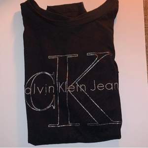 Säljer denna Calvin Klein T-shirt. Den är svart med ”metallic” silvrig logga och har normal passform