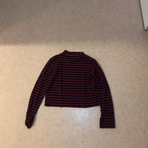 Randig magtröja svart röd - Hej! Säljer denna randiga svart röda magtröja som jag använde bara en gång. Den är sjukt fin och jätteskön!