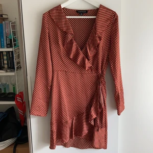 Prickig sidenklänning från Parisian  - Brunröd prickig klänning i fint material. Jätteskön och sitter fint, dragkedja i höften samt om man vill spänna åt med knytband. Min favoritklänning säljes nu pga blivit för liten. Använd 2-4 gånger. 