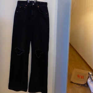 Jeans  - Svarta jeans med vida ben med hål vid knäna. Funkar för någon som är runt 170 cm lång. 