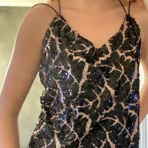Partytopp med paljetter - Ett perfekt party-linne med paljetter och smala band. Öppen och ganska djup i ryggen. Strl S. Aldrig använd. Nypris: 399.