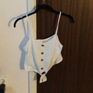 White Cami Crop Top - White cami crop top with brown buttons and a tie at the bottom. 🤍