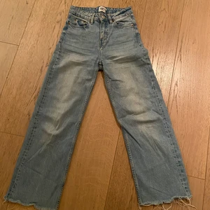 Hömidjade blåa jeans, raka & vida  - Intressekoll på dessa blåa (ljusblåa) vida och raka jeans från lager 157, modell lane. De är högmidjade och slutet av benen är klippt och trådigt (var så när jag köpte dem). De är välanvända men i bra skick. Storlek XXS. Nypris 300kr, säljer för 100, kanske går att pruta något. Frakt ingår ej. Kan skicka fler bilder vid intresse. 