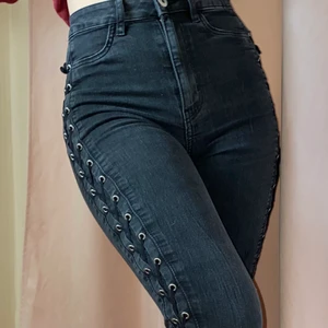 Jeans med snörning - Grå svarta jeans med korsad snörning längs med sidorna av benen och höfterna, storlek 34