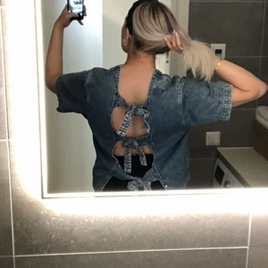 Jeans topp med öppen rygg - Topp från Monki i jeans-tyg med öppen rygg. Man knyter bak själv så det går att anpassa hur stort öppning man vill ha! Passar strl M 