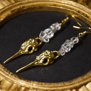 Örhängen fågelskalle  - Örhängen med guldiga fågelskallar och äkta bergskristall. Krokarna är nickelfria. 