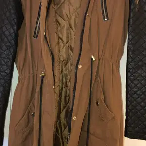 Lång brun jacka med svarta armarna 