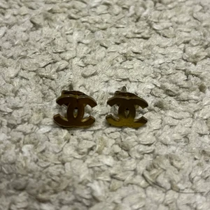 Örhängen  - Örhängen i guld med Chanel logga. Oanvända. Man känner på din att det är bra kvalite och hållbara. Relativt små men tunga för sin storlek. 