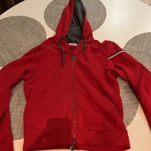Moncler hoodie röd, storlek M - Grymt snygg Moncler hoodie i eftertraktad röd färg! Svår att få tag på och är i skick 8/10. Har använts tiotal gånger endast sedan köp och har inga fel eller problem! 