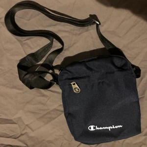 Blå Championväska!  - En blå axelväska från märket Champion! I bra skick. Den har en liten ficka fram. Väskan kostar 90kr plus frakt! 