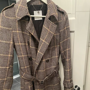 Rutig kappa - Skitsnygg lång kappa från märket Rino & Pelle i storlek 38. Använd 2 ggr förra vintern och säljer eftersom den inte kommer till användning. Kan frakta eller mötas i Stockholm. Nypris 1500kr