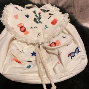 Söt zara ryggsäck  - En super söt ryggsäck med pärldetaljer och massa glada färger. Den skulle passa både en tjej som går i skolan eller en kvinna som har riktigt cool och färgglad stil, då hon kan ha ryggsäcken som en extra detalj för att göra outfitsen 100 gånger bättre eftersom att den är så lockande och söt!… den har också justerbara band så passar alla. Har inte använt den mycket alls men den har tyvärr fått lite fläckar på backsidan av ryggsäcken…. Glöm inte, köparen står för frakten! 