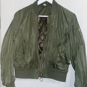 Militärgrön bomberjacka  - Säljer en grön bomberjacka från h&m. Den är använd många ggr men egentligen inga tecken på det, lite knottriga ärmmuddar men thats it. Guld detaljer och en lite tjockare bomber!