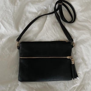 Svart väska - Svart väska i fakeskinn med gulddetaljer. Finns både långt justerbart band och ett mindre för att använda den som en clutch⚡️ fint skick men säljer pga flytt 