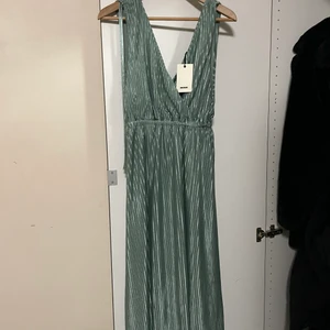 Oanvänd plisserad vadlång klänning - Klänningen är oanvänd och prislapp är kvar som det syns på bilden. Härlig grön färg. Klänningen är storlek S men passar en medium/large också om man inte vill ha den lika ”lös”.