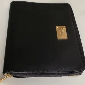 Micheal Kors väska i svart med stiliga gulddetaljer för en iPad. Inköpt på NK i Stockholm för ca 1500 kr. Använd 4 gånger. Finns inte att köpa i butik längre. Fint skick! Har även praktiskt utrymme för pennor, bok och annat. 25 cm x 20 cm. Kan absolut tänka mig att gå ner i pris vid smidig affär!
