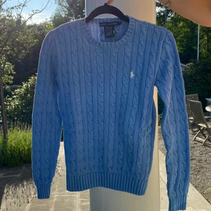 Kabelstickad blå Ralph Lauren tröja - Härlig kabelstickad tröja i den perfekta blåa färgen. Tröjan är i bra skick och har kommit i bra användning och är fortfarande lika skön i materialet som när jag köpte den!