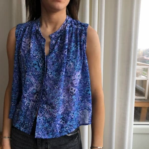 Blå blus - Blå blus från monki med detaljerat med blommor, knäpps fram till. Lila nyanser