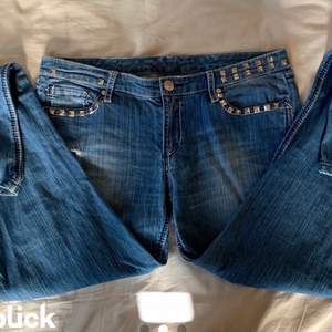 Blåa lätt utsvängda jeans m nitar, vissa som fallit bort. Midjemått 42cm, innebenslängd 82cm, hör av er vid frågor🥰
