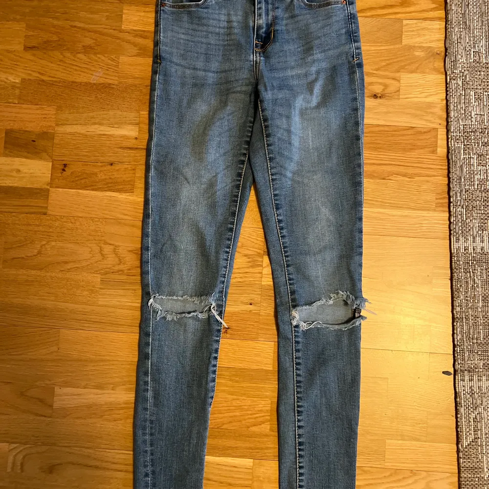 Ljusblåa tighta jeans, högmidjade med slitningar i knäna.. Jeans & Byxor.