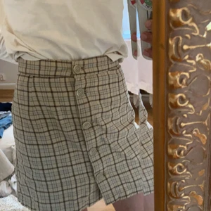 Rutig kjol med knappar! - Brun, beige och blå rutig kjol med knappar från monki, knappt använd. 