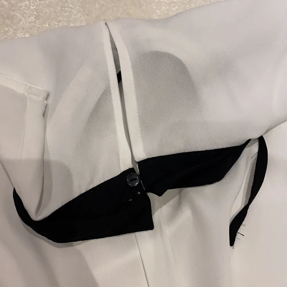 En vit blus med fin svart krage och rosset. Syns lite igenom men det är inga problem, det går bra att ha ett vitt eller svart linne under.. Blusar.