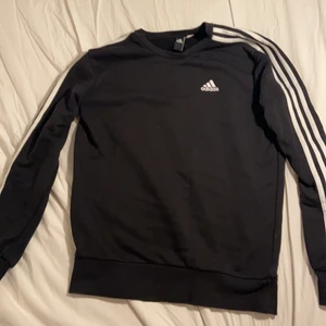 ADIDAS SVART SWEATSHIRT - Säljer en svart Adidas sweatshirt i utmärkt kondition. Endast använd några gånger och passar perfekt för lite kyligare väder. Adidas kläder är även bra för när man ska träna så den funkar för det även. Köptes för 500 kr men säljs för 399. Passar både S och M