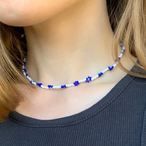 Pärlhalsband blommor - Hemgjort pärlhalsband med blommor. Halsbandet är 38 cm och av plasttråd med hasp som kan knäppas i nacken. 