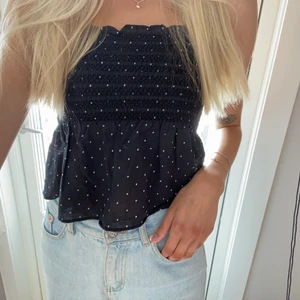 Prickig topp - Supergulligt, prickigt linne med resår runt bröstet och volang nertill. Smala band som går att justera längden på. Endast använd 1 gång!🥰