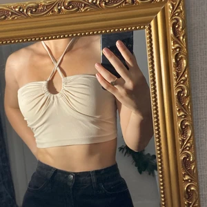 topp - En skitfin topp som är helt ny dvs aldrig använd. Man kan ha den på flera olika sätt(se bilderna) och går att knyta i nacken. Säljer pga inte kommit till användning. Färgen är beige med lite rosa underton.