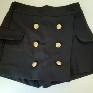 BERSHKA, kjol/shorts.  - Ser ut som en kjol, men sitter som ett par shorts. Svart med guldknappar. Bara använd en gång. 