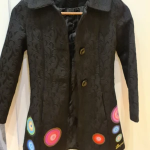 Kappa!! (Barn) - Säljer en väldigt fin svart kappa från desigual. Fram längst ner på kappan är det olikfärgade cirklar. Den är i storlek 9/10 år och jag skulle säga att det motsvarar ungefär 134/140. Denna kappa är i bra skick då den är använd ett fåtal gånger. Köparen står för frakt.