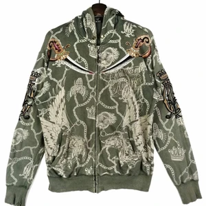 Ed hardy by christian audigier zip up - Ed hardy by christian audigier zip up hoodie. Oversized fit, sitter som L på mig som brukar ha strl S. Köp av en etsy säljare secondhand, därav lite sliten på armmudden. Inte använd sen den köptes secondhand.
