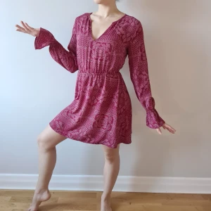 Röd mönstradklänning från Ivyrevel - Röd mönstradklänning från Ivyrevel, v-ringad, i ett lätt, skönt, luftigt material. Något tajt i resåren i ärmarna, rekommenderar storlek XS-S.