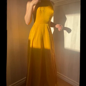 Gul balklänning, oanvänd  - Gul/guldig balklänning i jättefint material. Nypris ca 1000 kr exklusive tullavgifter, köpt från USA men helt oanvänd pga fel storlek.  Djup rygg med justerbara band och slits där fram. Fler bilder kan skickas privat!💕