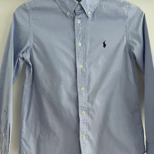 Ljusblå Ralph lauren skjorta, fint skick - Storlek: 14, använd fåtal gånger, inhandlad på NK i Stockholm, nypris 900kr, Skriv kommentar om du vill veta något mer!