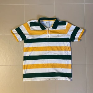 Randig Piké  - Randig pikétröja. Finns en liten fläck på ena ärmen (se sista bild). Tröjan är i storlek L men liten i storleken