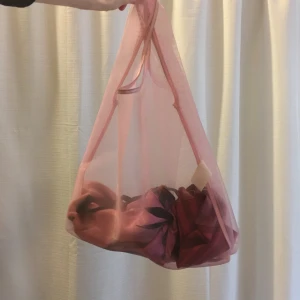 Ljusrosa genomskinlig kasse GRATIS FRAKT - Kasse i ljusrosa polyester. Genomskinlig. Lite slitage och smuts vid handtagen och vissa fläckar på kassen, i övrigt hel. 