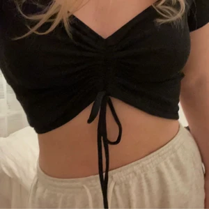 Svart topp med knytning - Jättesöt svart topp med knytdetalj som går att ”dra upp” hur mycket man vill. Man kan ha den mer som en croppad t shirt eller en topp som i princip bara täcker brösten och axlarna (som första bilden) Skriv privat för fler bilder ❤️