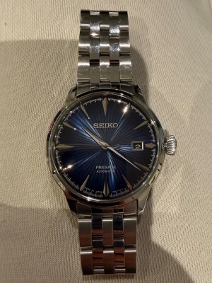 Seiko Presage automatisk klocka - Snygg Seiko Presage automatisk klocka med blå urtavla och datumvisning. Klockan har ett rostfritt armband i silver och transparent baksida som visar urverket. Perfekt accessoar för dig som gillar stilren och klassisk design.