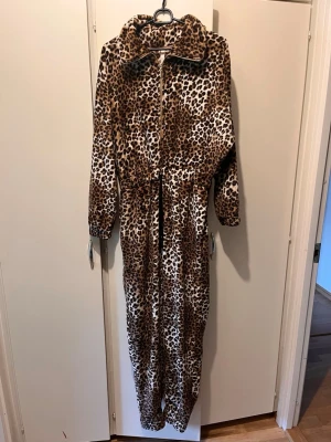 Onepiece strl XS Hunkemöller  - Onepiece mysdress i mjukt leopardmönstrat tyg. Storlek XS. Guldfärgad dragkedja fram och knytning i midja. Mycket bra skick. 