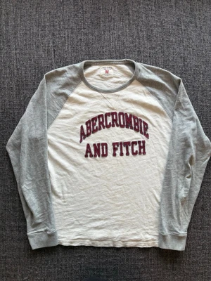 Abercrombie & fitch longsleeve  - Sjukt eftertraktad Abercrombie & Fitch longsleeve i grå/vit – sällsynt 2000’s modell, stl M. Fint skick och sitter riktigt bra, perfekt till vardag 🌿  Kan även gå ner lite i pris vid snabb affär ✌️ Skickas inom 24h 📦