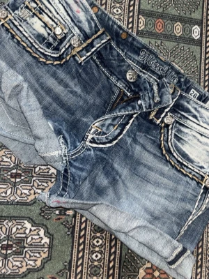 Blå jeansshorts från Miss Me - Säljer ett par blå jeansshorts från Miss Me med slitna detaljer och kontrasterande sömmar. Shortsen har flera fickor med dekorativa knappar och broderade detaljer. (Ett par skinny jeans jag har klippt. Lite konstigt klippta men ser helt perfekta ut om man viker upp dem så som jag gjort på bilderna.❤️)