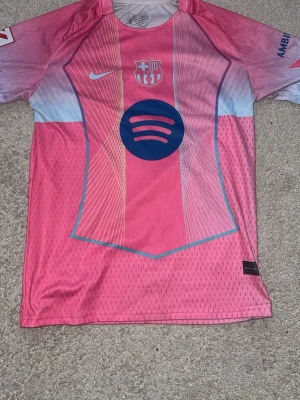 Barcelona lamine yamal - Säljer en FC Barcelona matchtröja i rosa och ljusblått från Nike med Spotify-logga på bröstet och Lamine Yamal 10 på ryggen. Tröjan har klubbmärke, sponsortryck och är tillverkad i lätt, ventilerande material. Perfekt för fotbollsträning eller att bära som supporter. Pris kan diskuteras! Köpt för800kr