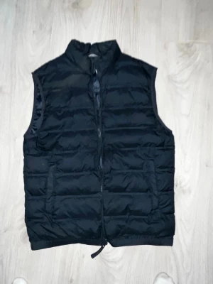 Mörkblå vest från Zara  - Stilren mötkblå dunväst med hög krage och dragkedja framtill. Västen har två fickor på sidorna och quiltad design med horisontella sömmar. Perfekt för lager-på-lager och enkel att matcha med olika outfits. Storlek s och i perfekt skick