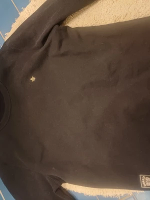Svart sweatshirt från morris  - Snygg mörkblå sweatshirt från morris med liten broderad logga på bröstet. Tröjan har rund halsringning och ribbade muddar. Perfekt för en stilren och avslappnad look.