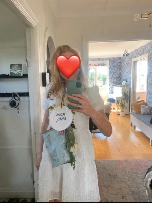 Vit kort klänning med puffärm - Söt vit kort klänning med puffärmar och struktur i tyget. Klänningen har en feminin siluett och rund halsringning. Perfekt för somriga tillfällen och studentfirande.