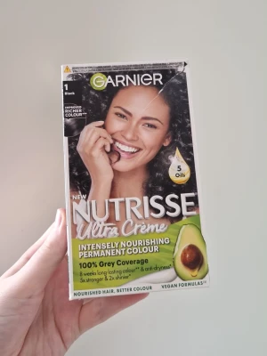 Garnier Nutrisse Ultra Crème svart hårfärg - Permanent hårfärg från Garnier Nutrisse Ultra Crème i nyansen svart. Innehåller 5 oljor och ger intensiv näring samt 100% gråhårstäckning. Vegansk formula och långvarigt resultat. Förpackning är självklart oöppnad och oanvänd
