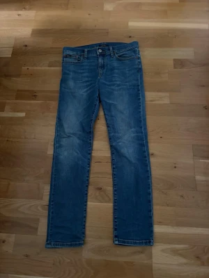Ralph Lauren blå slim fit jeans - Snygga blå slim fit jeans med klassisk femficksdesign och lätt slitna detaljer på framsidan och baksidan. Jeansen har normal midja och raka ben. Perfekta för en avslappnad och trendig look. Storlek 14 i barn. Se mått på bilderna